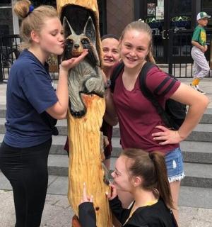 a group of girls standing around a totem pole