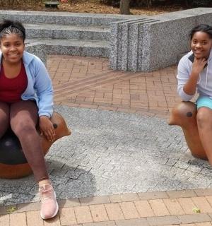 two young women sitting onorses in a playground