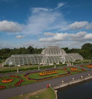 a large glass greenhouse with flowers in a park
