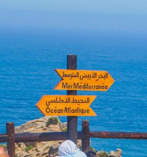 海边有一块带有指向不同方向的箭头的标志