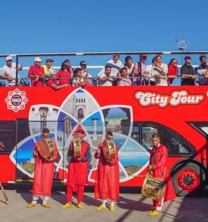 a group of people standing in front of a double decker bus