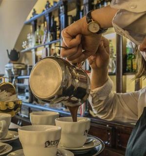 žena nalévá kávu do šálků v kavárně