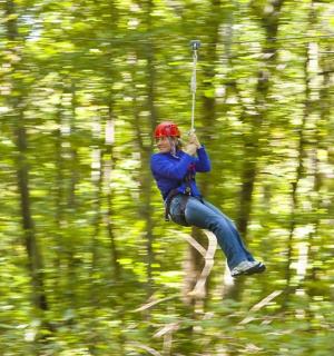 một người đang bay qua rừng trên đường trượt zipline