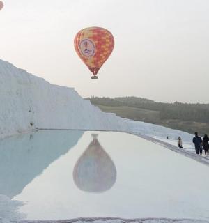 a hot air balloon flying over a pool of snow