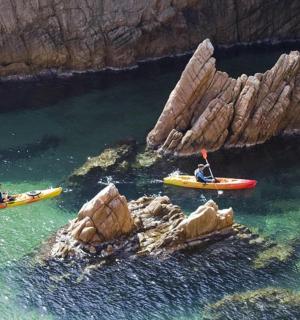 dva lidé v kajacích ve vodě vedle skal