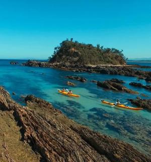 a group of boats in the water near a rocky island