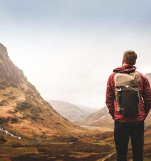 a man standing on top of a mountain looking at a valley