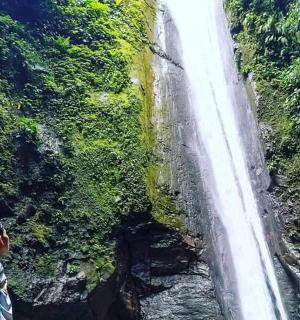 muž stojící na útesu a dívající se nahoru na vodopád