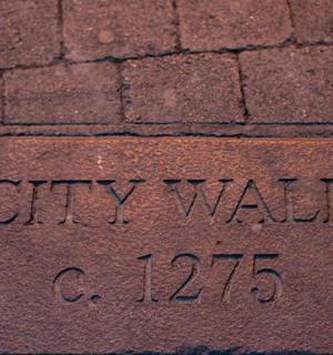 cihlový chodník s cedulí s nápisem „městská zeď“