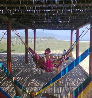 žena sedící v houpací síti na pláži