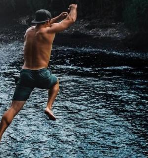 a man standing in a river with his arms in the air