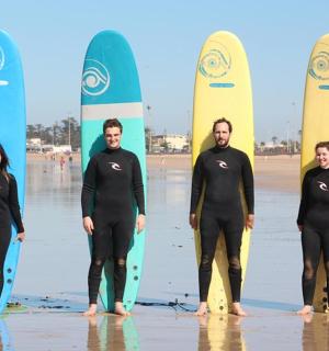 skupina lidí stojících na pláži se surfovými prkny