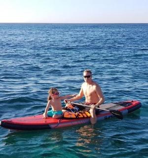 一名男子和一名女孩在水中的一艘红色明轮船上