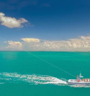 a boat in the ocean flying a kite
