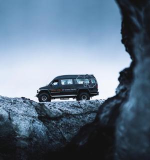 一辆黑色吉普车停在岩石顶上