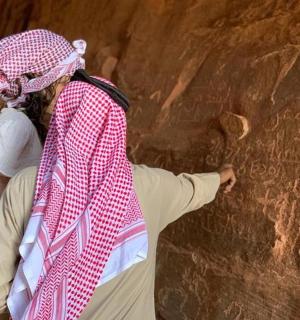 一位女士站在一堵写有字的墙旁