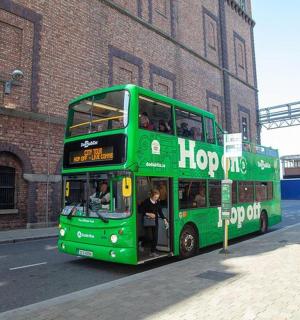 一辆绿色双层巴士停在一栋砖砌建筑旁边