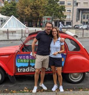 a man and a woman standing next to a small car