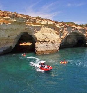 a group of people in a boat in the water near a cave