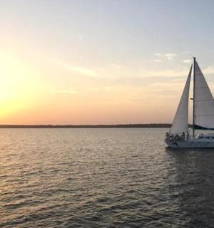 一艘帆船在水面上航行,背景是日落
