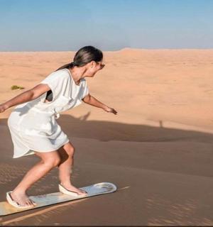 a woman standing on a surfboard in the desert