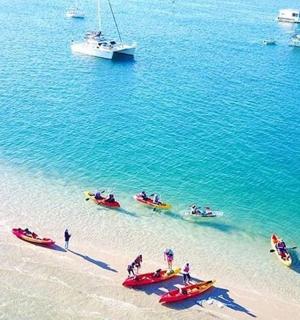 Grupa ludzi na plaży z łodziami w wodzie