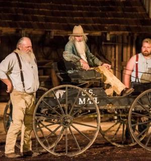 skupina mužů stojících kolem koňského povozu