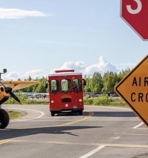a yellow airplane and a red bus on a road