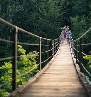 skupina lidí jdoucích po visutém mostě