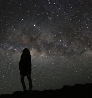 člověk stojící na kopci a dívající se na vesmír
