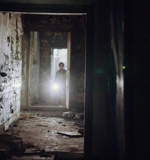 一名男子站在走廊里，手里拿着一盏灯