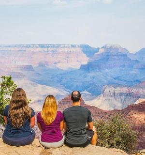 skupina ľudí sediacich na okraji Grand Canyonu