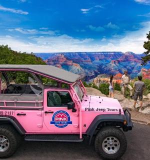 a pink jeep parked in front of the grand canyon