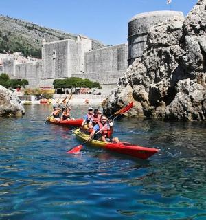 一群人划着皮划艇在河上漫步，河上有一座城堡
