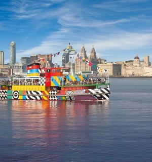 a colorful boat sitting in the water with a city