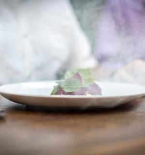 木桌上放着一盘食物,一个人拿着叉子