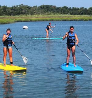 tři lidé paddleboardují na jezeře