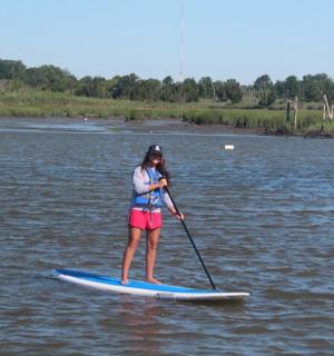 žena stojící na paddleboardu ve vodě