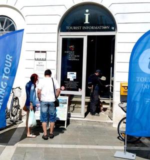 两个人站在一栋建筑前，旁边还有自行车