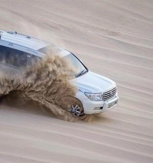 a white suv driving through the mud in the desert