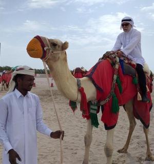 một người đàn ông đứng cạnh một người đang cưỡi lạc đà