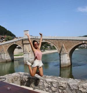 a man standing on a stone wall next to a bridge