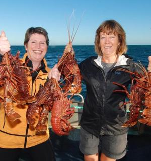 两个人在船上举着龙虾