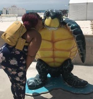 osoba objímající sochu želvy