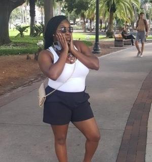 žena v bílé košili a kraťasech mluvící po mobilním telefonu