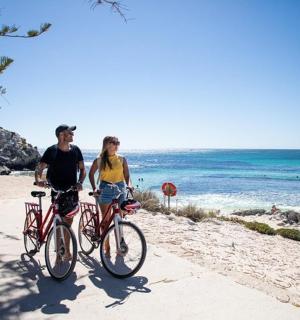 a man and a woman riding bikes on the beach