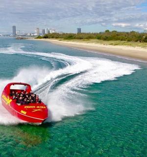 a red boat in the water next to a beach