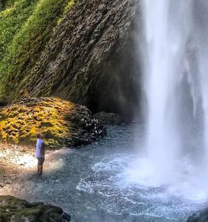 一名男子站在瀑布旁的水中