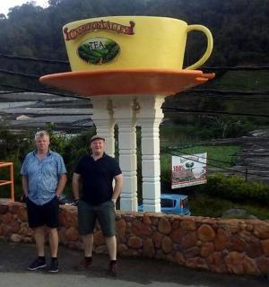 two men standing in front of a giant coffee cup statue