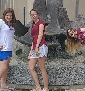 three women standing in front of a fountain with umbrellas
